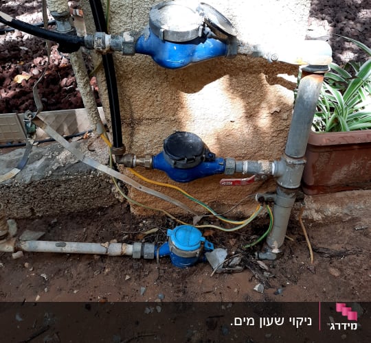 מד מים כחול מחובר לצינורות על קיר חיצוני
